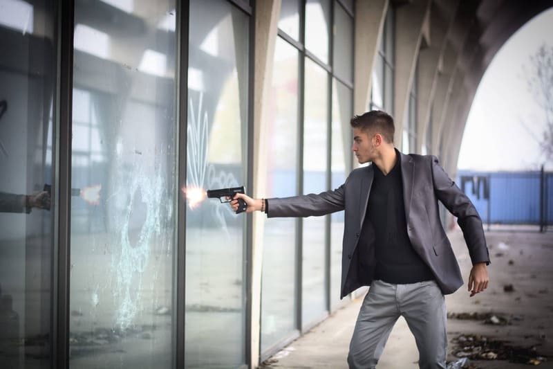 folie antiefractie persoana cu pistol care trage asupra unui geam securizat